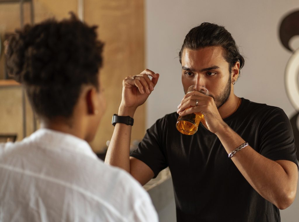 unhappy man drinking alcohol with friend addiction