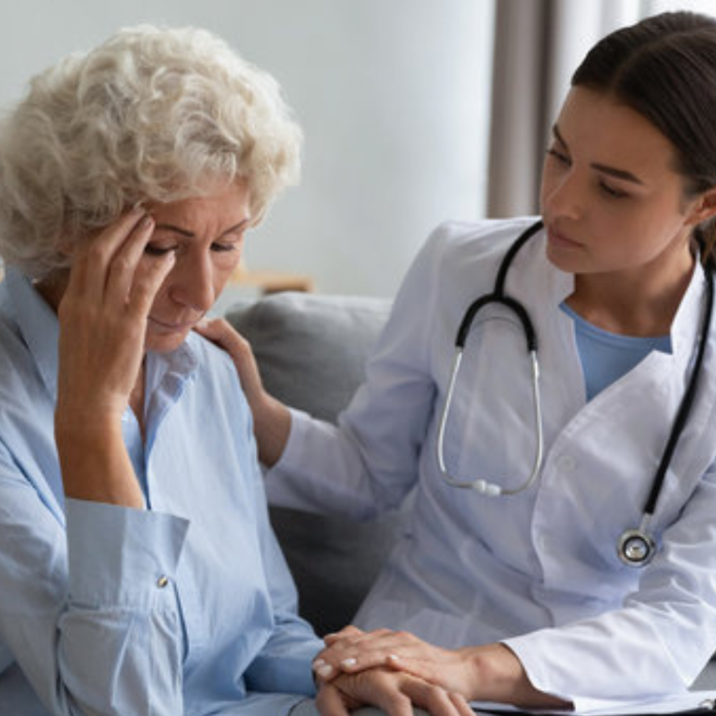 this is an image of an elderly lady who is clearly struggling being spoken to by her doctor, discussing her mental health.The doctor is trying t support her.