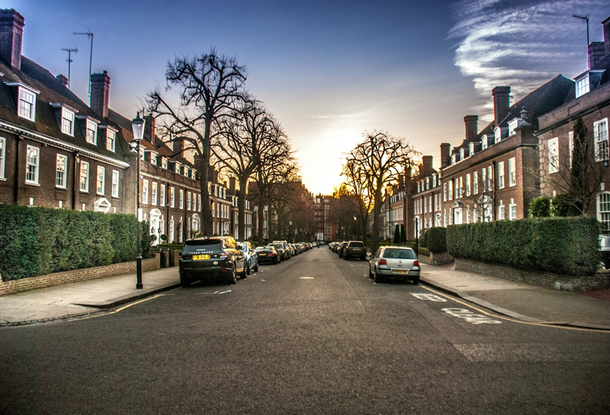 A quiet residential London street at sunset, with terraced houses and parked cars, symbolizing everyday life and the potential for cheap solar power in local communities.