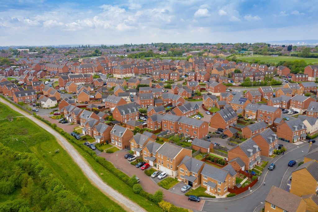 Aerial view of a residential development with red-brick homes, roads and nearby green space. Gives an example of what integrated design looks like. 