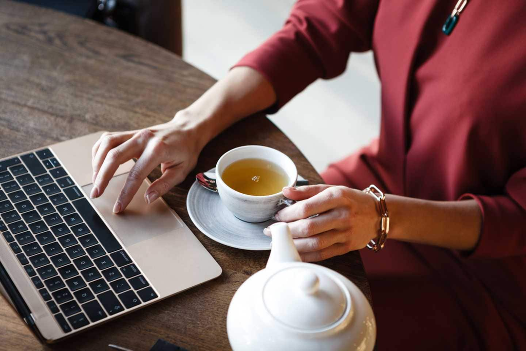 Cup of tea on an office desk beside a laptop and notebook, creating a warm and professional workspace atmosphere. A myth that apprentices only make tea.